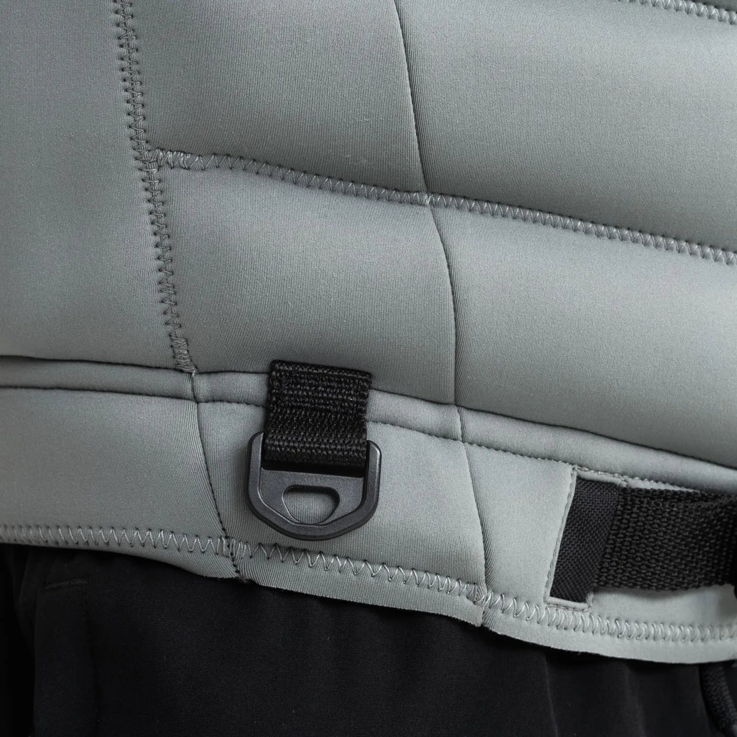 Close-up of a gray quilted jacket with a black strap and buckle detail.
